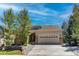 Charming beige home with a two-car garage, stone accents, and a well-manicured front yard under a bright blue sky at 740 Deer Clover Cir, Castle Pines, CO 80108