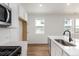 Modern kitchen featuring white cabinets, stainless steel appliances, quartz countertops, wood floor and large sink at 5785 N Jericho Way, Aurora, CO 80019