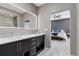 Modern bathroom boasts a double vanity with black cabinets, sleek fixtures, and a well-lit mirror, with a view into the bedroom at 11025 Watermark St, Parker, CO 80134