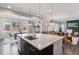 Bright, open kitchen with island bar, stainless appliances, and adjacent dining and living spaces at 11025 Watermark St, Parker, CO 80134