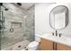 Sleek bathroom features modern vanity, glass-enclosed shower with unique tile, toilet and oval mirror at 1823 W 35Th Ave, Denver, CO 80211