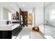 Bright bathroom showcasing a soaking tub, dual sink vanity, and wood accent wall with access to closet at 1518 S Columbine St, Denver, CO 80210