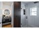 Modern bathroom featuring a glass shower, wood accents, and a stylish round mirror over a floating sink at 1518 S Columbine St, Denver, CO 80210