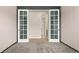 Empty bedroom features french doors leading to bath and closet; gray walls and carpet at 6514 Agave Ave, Castle Rock, CO 80108