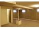 Spacious basement features paneled walls, carpet, support column, and a door leading to another room at 10759 Ogden St, Northglenn, CO 80233