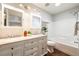 Well-lit bathroom with double sinks, granite countertops, white cabinets, and a bathtub with shower at 9811 Gatesbury Cir, Highlands Ranch, CO 80126