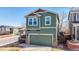 Two-story green home with a two-car garage, brick accents, covered porch, and well-kept lawn at 9811 Gatesbury Cir, Highlands Ranch, CO 80126