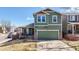 Two-story home with a two-car garage, a covered porch, green siding and brick accents and well-kept lawn at 9811 Gatesbury Cir, Highlands Ranch, CO 80126