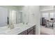 Bright bathroom with double sinks and a view into the home office at 16321 Clayton St, Thornton, CO 80602