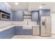 Charming kitchen features blue cabinets, stainless appliances, and a farmhouse sink at 16321 Clayton St, Thornton, CO 80602