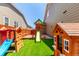 Fun playground with a slide and playhouse surrounded by green turf in a secure backyard at 16321 Clayton St, Thornton, CO 80602