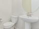 Powder room features a pedestal sink, toilet, and a round mirror at 16321 Clayton St, Thornton, CO 80602