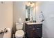 Clean half bathroom features a modern vanity, toilet, and decorative mirror at 7203 W Pacific Ave, Lakewood, CO 80227