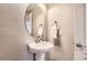 Elegant powder room featuring a pedestal sink, oval mirror, textured walls, and modern fixtures at 4545 S Monaco St # 436, Denver, CO 80237