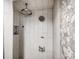Tiled shower with rainfall shower head, pebble accents, and modern fixtures at 7350 Dale Ct, Westminster, CO 80030