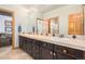 Dual sink bathroom vanity with wooden cabinets and large mirror at 12161 S Leaning Pine Ct, Parker, CO 80134