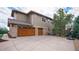 Three-car garage with paneled doors, plus a basketball hoop and large parking pad at 12161 S Leaning Pine Ct, Parker, CO 80134