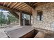 Covered outdoor patio with stone supports, hot tub, and stone privacy wall at 12161 S Leaning Pine Ct, Parker, CO 80134
