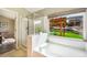 A luxurious bathroom boasts a soaking tub, a glass-enclosed shower, and a window offering views of the outdoor space at 15635 Dawson Creek Dr, Monument, CO 80132