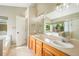 Bright bathroom featuring a double sink vanity, a large mirror, and a window offering natural light and scenic views at 15635 Dawson Creek Dr, Monument, CO 80132