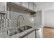 Close-up of a kitchen sink, with stone countertops and patterned backsplash at 1336 Sable Blvd, Aurora, CO 80011