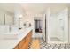 Bright bathroom featuring double sinks, wood cabinets, patterned floor, and walk-in shower with glass door at 1590 Little Raven St # 702, Denver, CO 80202