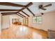 Bright open-concept living room with wood beam ceiling, hardwood floors, and natural light from windows and access to the yard at 7700 E Oxford Ave, Denver, CO 80237