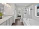 Bright main bathroom featuring double sinks, a soaking tub, and glass enclosed shower with bench at 2464 Garganey Dr, Castle Rock, CO 80104