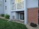 Exterior view of condo, showing gray siding, brick detail, and small fenced area with a sliding glass door at 7665 E Eastman Ave # 104A, Denver, CO 80231