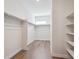 Bright walk-in closet with wooden floors, white walls, and a small window providing natural light at 14337 Shasta Daisy Pt, Parker, CO 80134