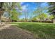 A spacious backyard with a large grassy area, mature trees, and a pergola-covered patio at 11305 W 78Th Dr, Arvada, CO 80005