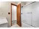 Bathroom including a white tub and shower with sliding doors and open doorway at 11305 W 78Th Dr, Arvada, CO 80005