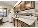 Kitchen with dark wood cabinets, white countertops, stainless steel double sink, and backyard window at 11305 W 78Th Dr, Arvada, CO 80005