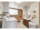 Functional laundry room with washer, dryer, and adjacent bathroom with a wooden vanity at 11305 W 78Th Dr, Arvada, CO 80005