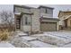 Two-story home featuring stone accents, stylish front door, and attached two car garage with snowy landscaping at 17265 E 110Th Ct, Commerce City, CO 80022