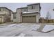 Two-story home featuring stone accents and an attached two car garage with snowy landscaping at 17265 E 110Th Ct, Commerce City, CO 80022