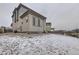 Side view of a two-story home with gray siding, snow-covered yard, and fence at 17265 E 110Th Ct, Commerce City, CO 80022