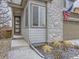 Close up view of the home's front porch featuring stone accents, modern door, and snowy landscaping at 17265 E 110Th Ct, Commerce City, CO 80022