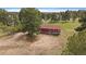 Aerial view of the home with a red roof and wood siding, nestled among mature pine trees at 3337 Ponderosa Rd, Franktown, CO 80116