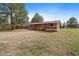 Exterior featuring wood siding, red roof, small deck, and mature pines in a treed setting at 3337 Ponderosa Rd, Franktown, CO 80116