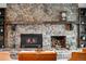 Close-up of a stone fireplace with a wooden mantel, built-in shelving, and a cozy fire burning at 6389 S Monaco Ct, Centennial, CO 80111