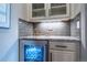 Bar area with granite counters, wine cooler, tile backsplash, and glass front cabinets at 8463 S Quemoy Ct, Aurora, CO 80016