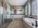 Spa-like bathroom features a glass-enclosed shower, soaking tub, double vanity, and modern finishes at 8463 S Quemoy Ct, Aurora, CO 80016