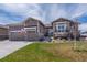 Charming exterior showcases stone accents, three-car garage, well-maintained lawn, and beautifully landscaped front yard at 8463 S Quemoy Ct, Aurora, CO 80016