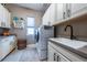 Well-lit laundry room with white cabinets, modern washer and dryer, and grey counter tops with sink at 8463 S Quemoy Ct, Aurora, CO 80016