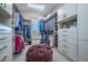 Large walk-in closet featuring custom shelving and storage for clothing, shoes, and accessories, with a central ottoman at 8463 S Quemoy Ct, Aurora, CO 80016