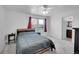Cozy bedroom features a large bed, neutral carpet, and a bright window with red curtains at 853 Mockingbird St, Brighton, CO 80601