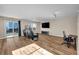 Bright living room with hardwood floors, a sliding glass door to the backyard, and a wall-mounted TV at 853 Mockingbird St, Brighton, CO 80601