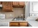 Small kitchen with wood cabinets, stainless steel sink, and stacked washer/dryer at 1180 Yosemite St # 104, Denver, CO 80220