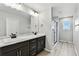 Bathroom featuring a double sink vanity, shower, and a view to outside at 6513 Dry Fork Cir, Frederick, CO 80516